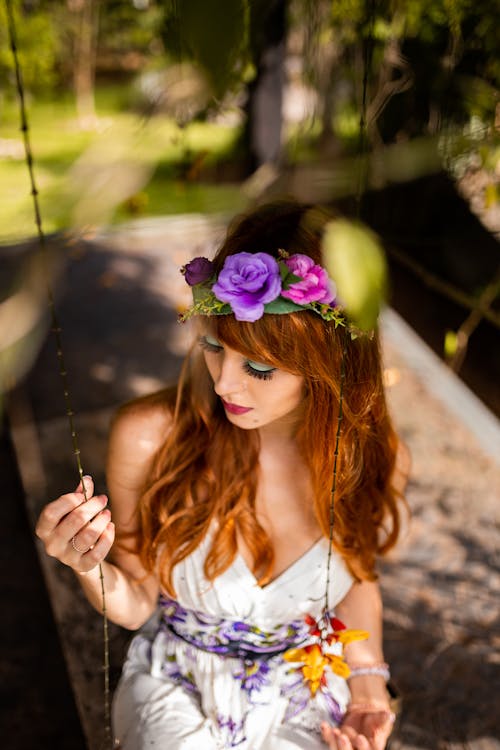 High-Angle Photo of Woman Wearing White Dress Sitting on Swing