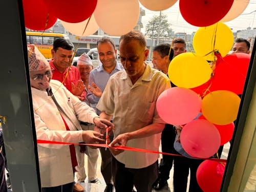 A man cutting a ribbon with balloons