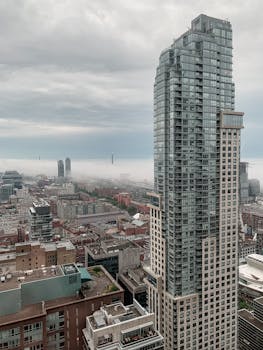 在多云的天空下，一座突出的现代摩天大楼矗立于多伦多城市天际线鸟瞰图中