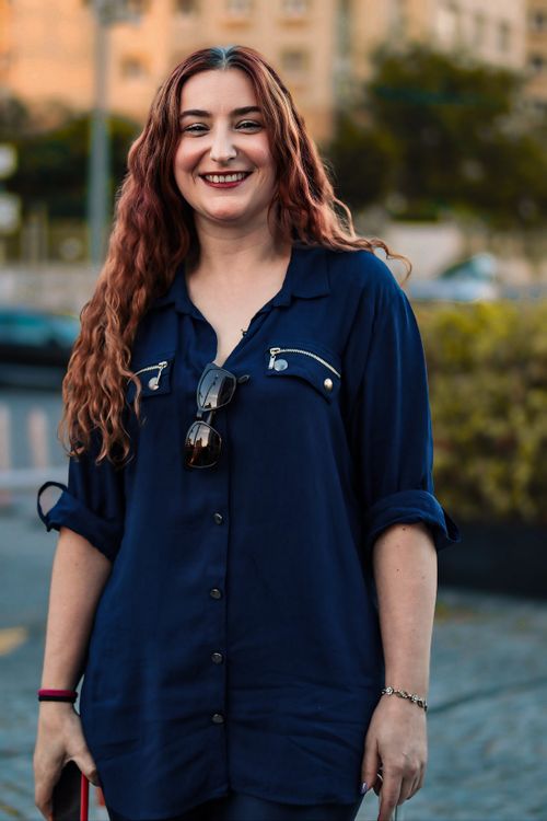 Free A cheerful woman with wavy hair smiles in an urban park. Captured outdoors. Stock Photo