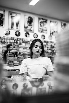 一名女子在唱片店里浏览唱片，黑白拍摄营造出复古感