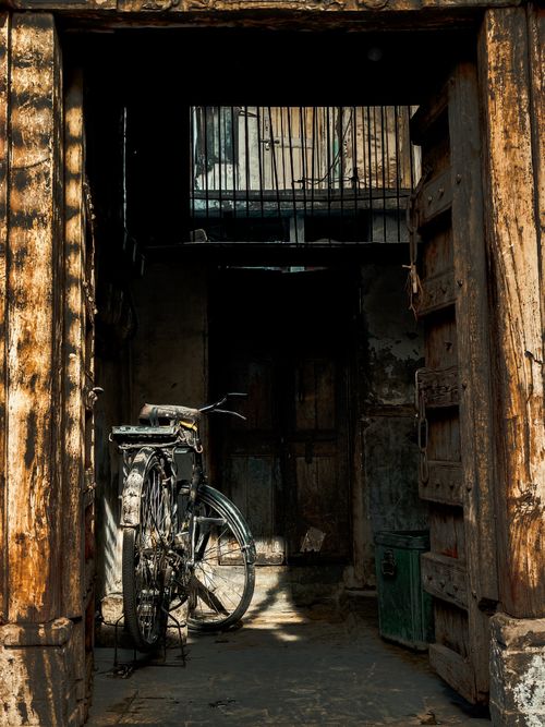 Free A rusty bicycle parked inside an abandoned, weathered building with wooden doors. Stock Photo