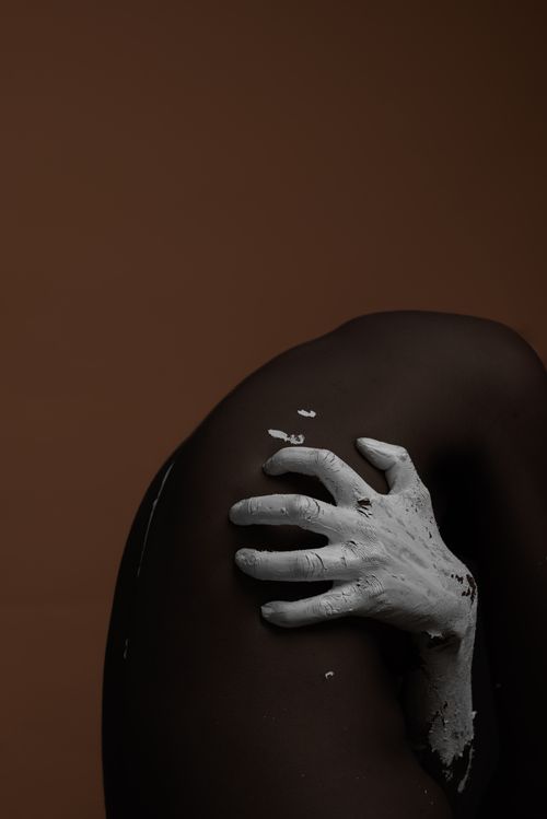 Free Conceptual studio shot of a white-painted hand touching black skin, exploring contrast and texture. Stock Photo