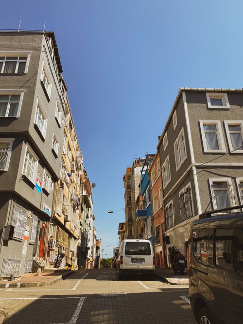 Free A bright city street flanked by colorful residential buildings under a clear sky. Stock Photo