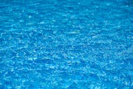 阳光下，游泳池里蓝色的水纹理明亮而清澈