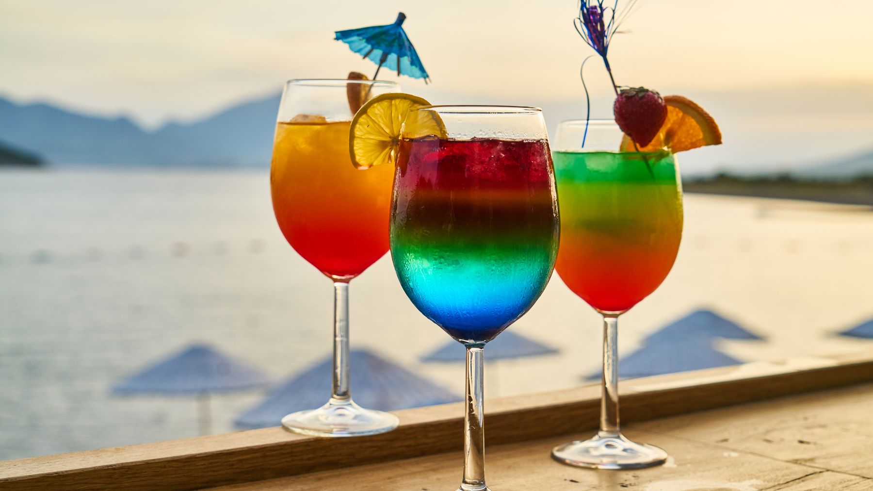 Colorful cocktails with garnishes at a sunset beach bar, perfect for tropical vacations.
