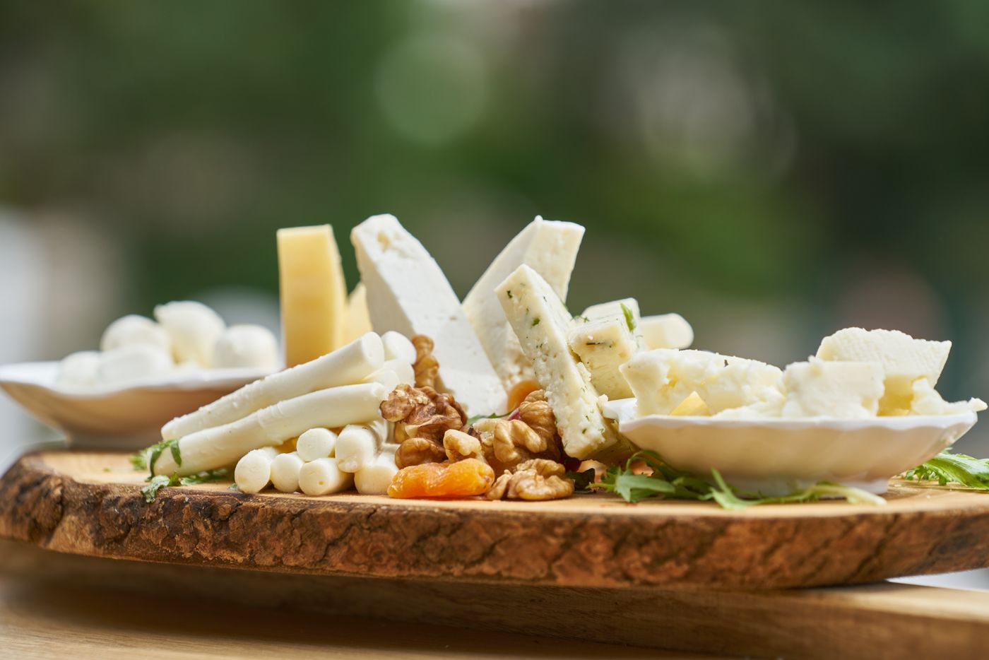 Cheese board with nuts on olive wood, face-free