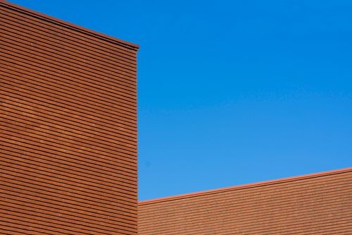 Free Modern brick building with geometric pattern against a clear blue sky, showcasing architectural design. Stock Photo