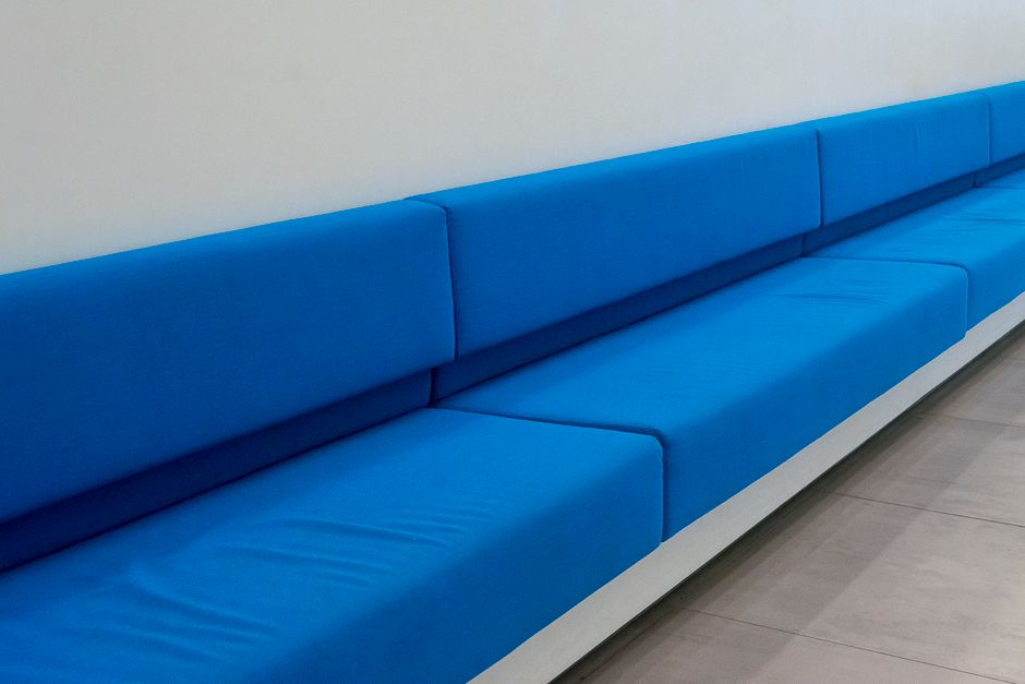 Long blue minimalist sofa seating against a white wall in a modern room.
