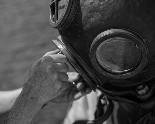 A black and white photo of a man wearing a diving helmet