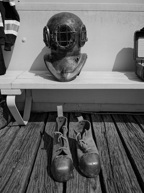 A diving helmet and a pair of shoes on a bench
