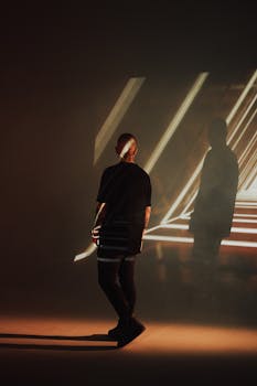 Fashion photography featuring a man in a studio with creative light patterns casting a shadow.
