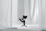 A camera tripod with a white curtain behind it