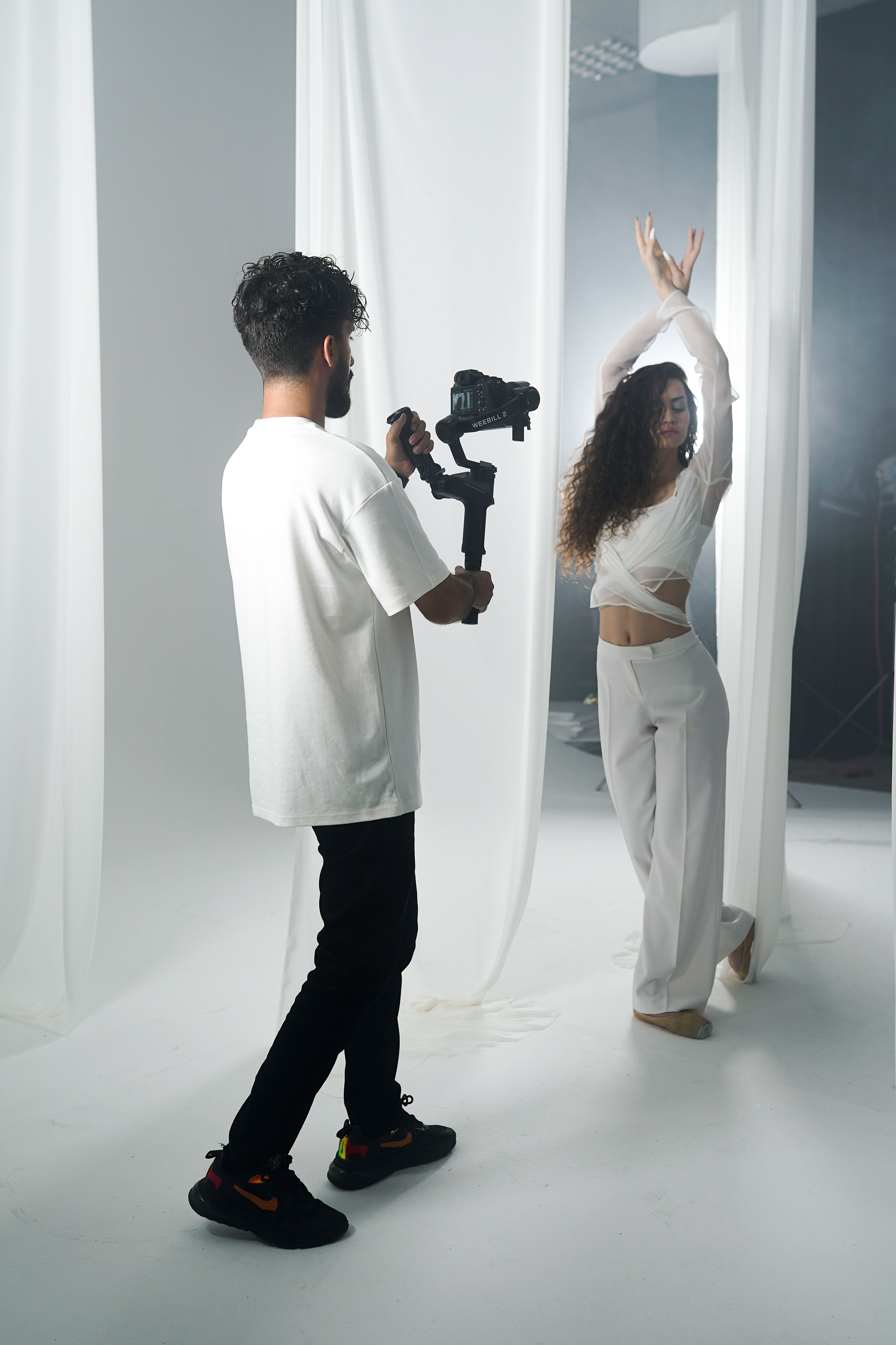 A woman dances as a videographer films in a stylish studio environment.