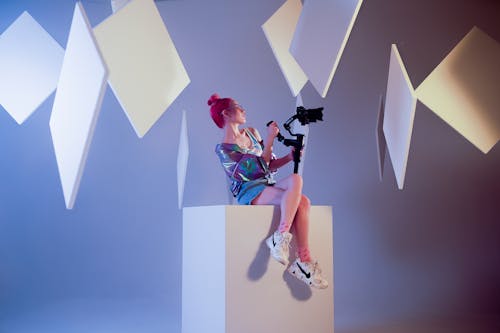 A woman sitting on top of a cube with a camera