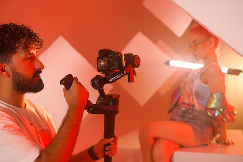 A man with a camera and a woman with a red light