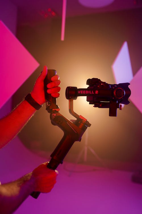 A person holding a camera in front of a purple light