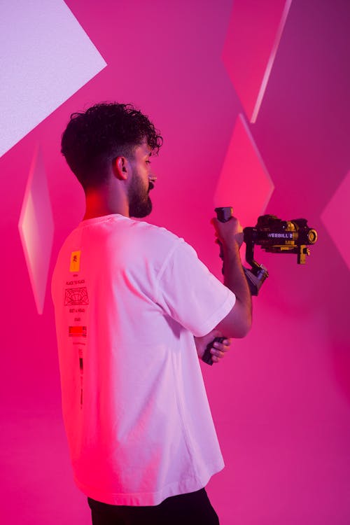 A man holding a camera in front of pink walls