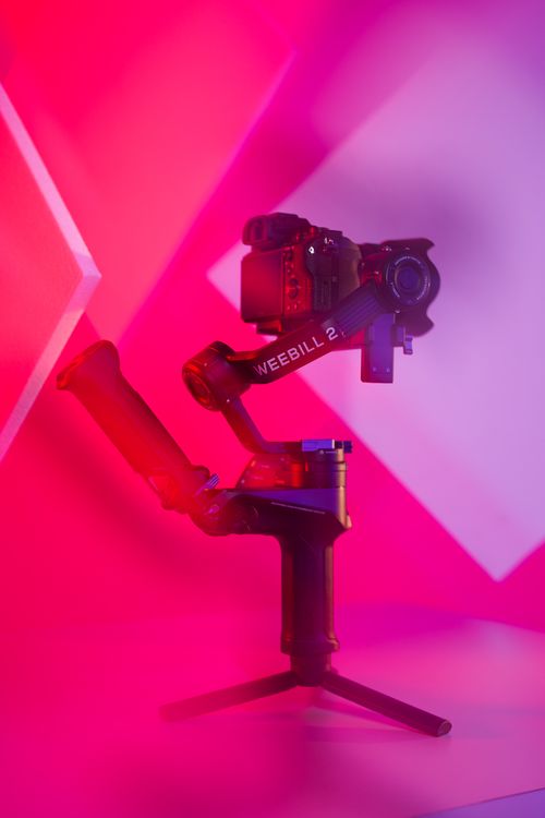 Free Colorful studio shot of a camera mounted on a Weebill 2 gimbal in pink lighting. Stock Photo