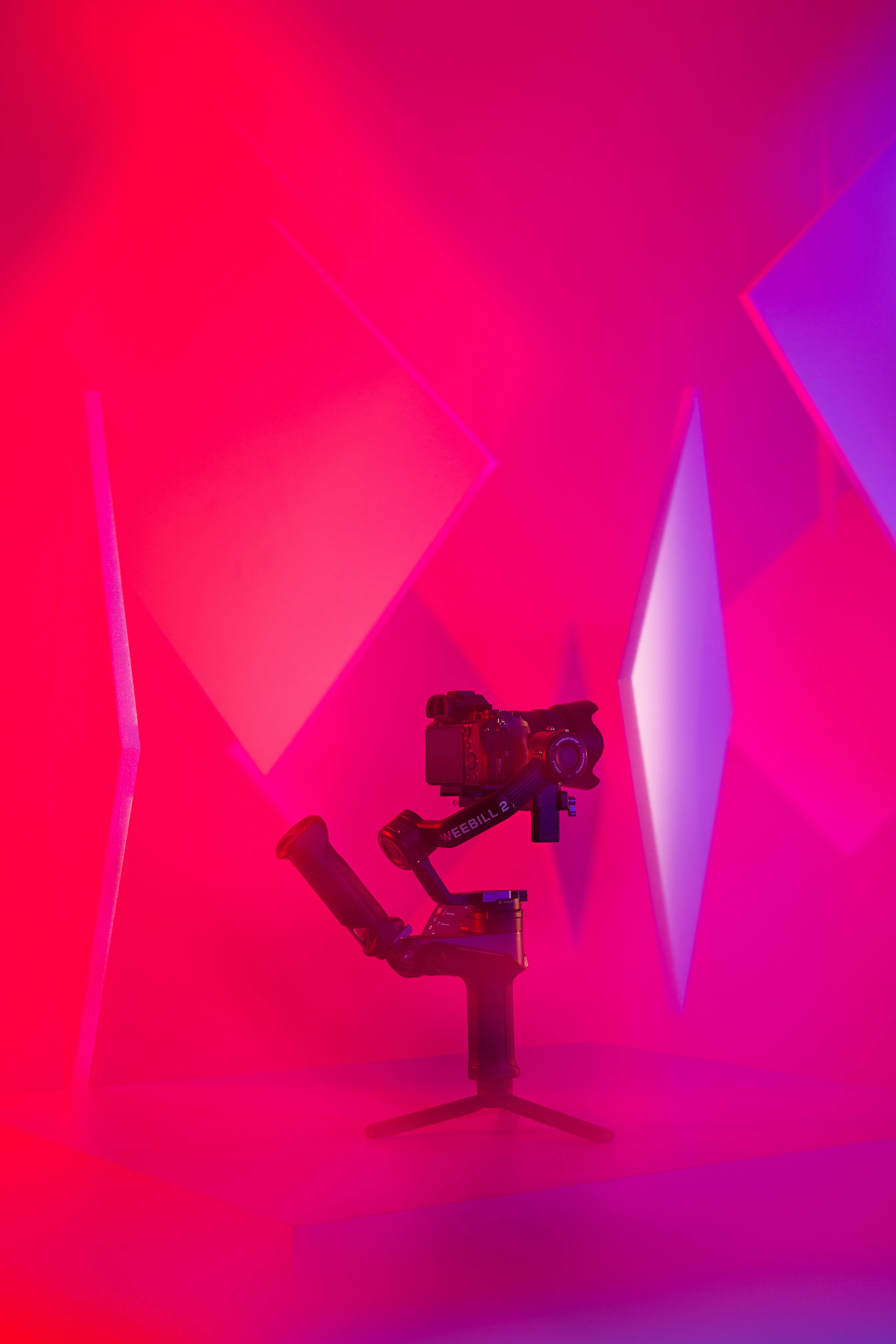 Camera on gimbal with vibrant purple and red studio lighting showing cinematography equipment