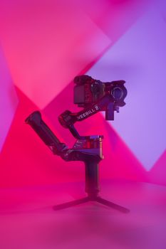 A sleek camera gimbal showcased against vibrant studio lighting for an artistic tech concept.