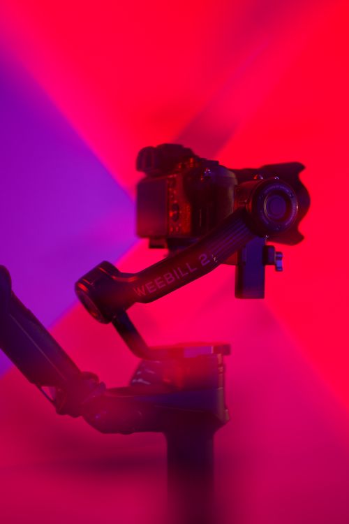 Free Modern camera on gimbal with bold red and purple lighting for a futuristic look. Stock Photo