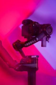 A modern camera mounted on a Weebill 2 gimbal in a studio with vibrant lighting.