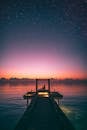 Silhouette Photo of Person Sitting on Boardwalk At Sunset