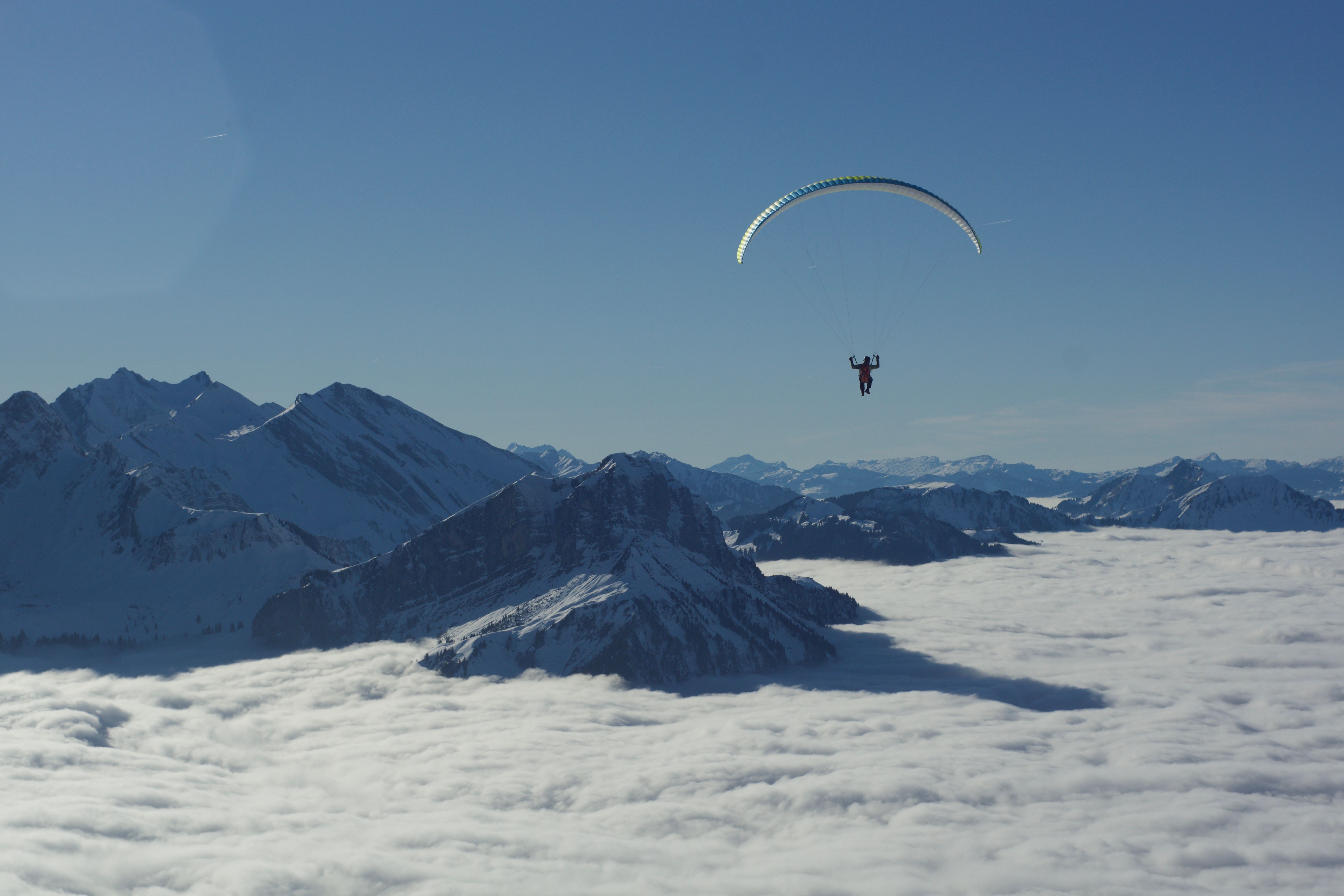 Person Parachuting over Cloud and Mountains Peaks · Free Stock Photo