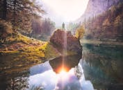 一个人坐在岩石上，俯瞰奥地利森林中反光的湖泊，四周风景宁静