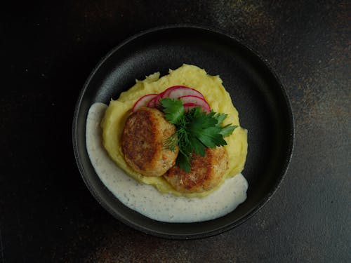 A plate of food with a piece of fish and a garnish