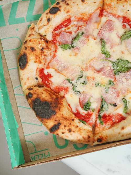 A pizza in a box with a green lid
