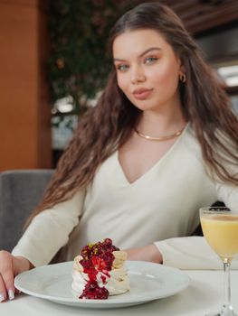Stylish young woman savoring a delicious dessert in an elegant restaurant setting.