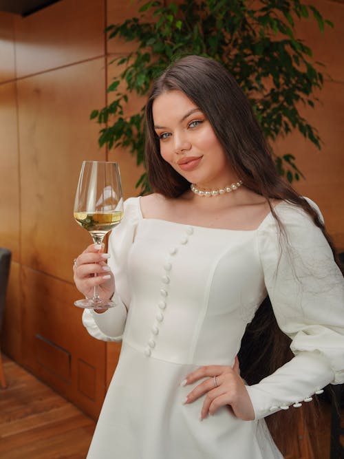 A woman in a white dress holding a glass of wine