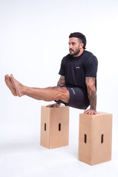 Adult male athlete showcasing strength with calisthenics using wooden blocks in studio.