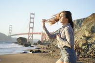 一名年轻女子站在海滩上，背景是标志性的金门大桥