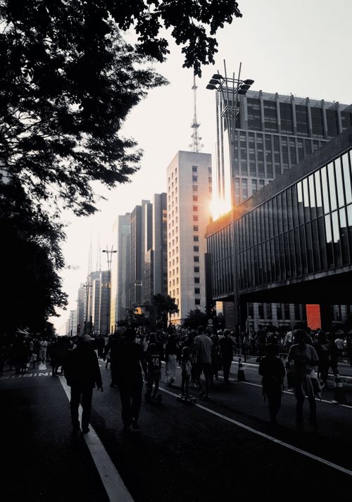 Free Crowded city street with modern buildings at sunset. Perfect urban life depiction. Stock Photo