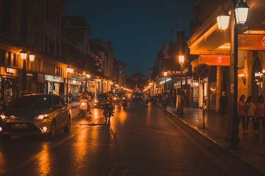 夜晚，温暖的城市灯光下，街道上行驶着汽车和摩托车