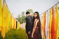 一对年轻夫妇手牵着手，穿过宁静户外环境中五颜六色的布