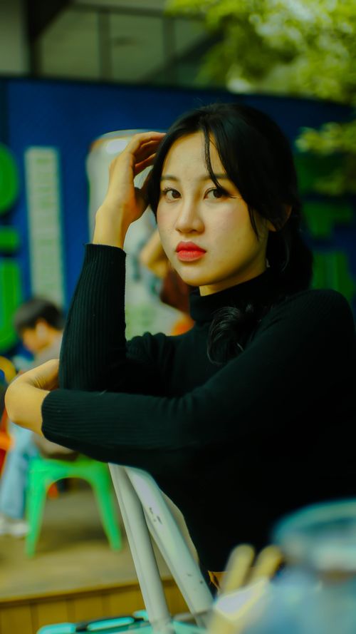 Free Elegant portrait of a young woman in a black sweater sitting indoors. Stock Photo
