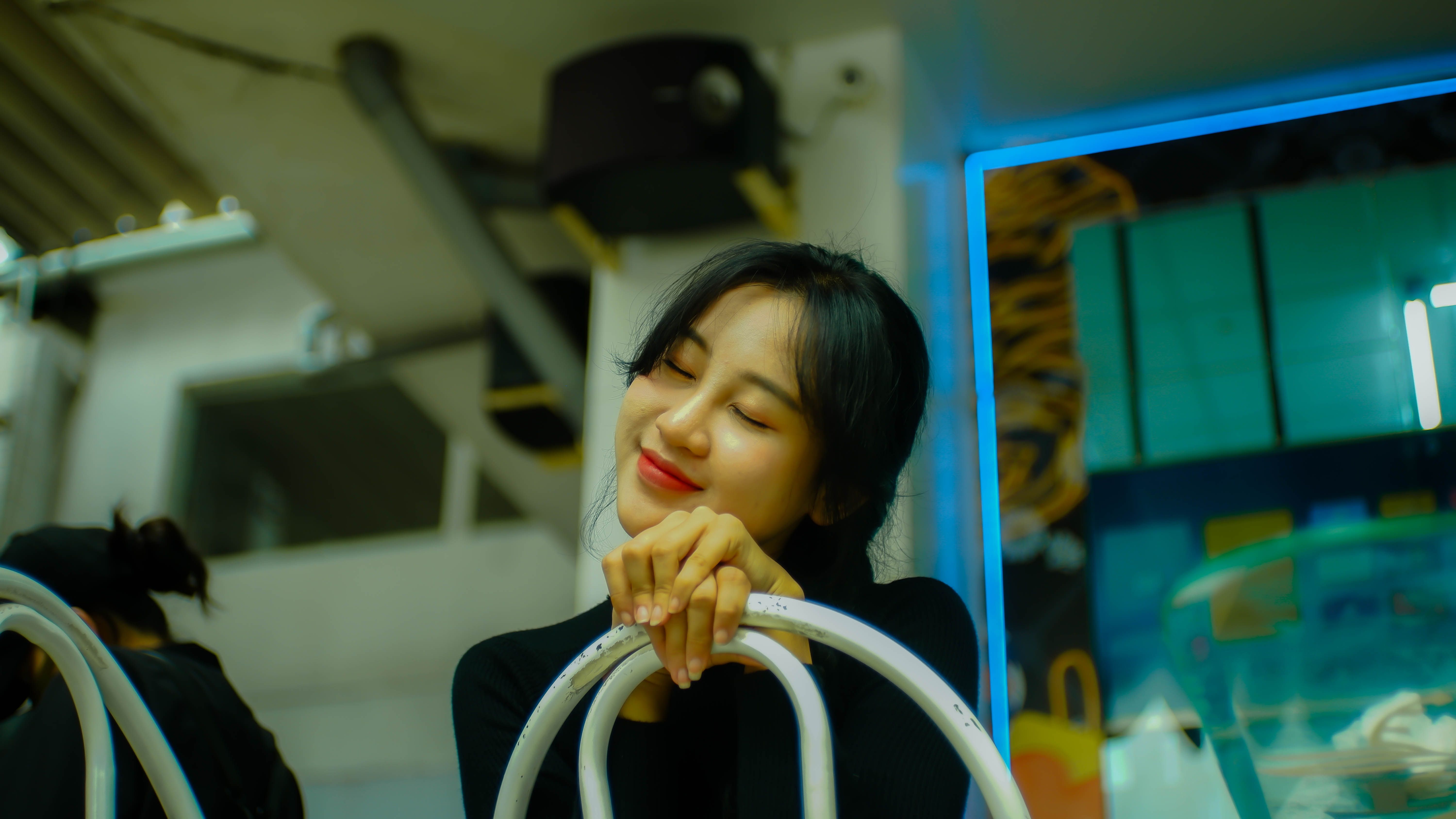Charming woman with eyes closed and smiling indoors, exuding warmth and joy.