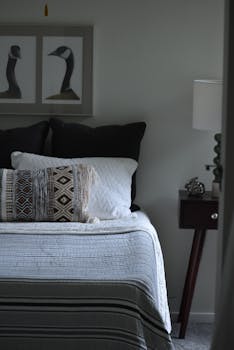 Stylish contemporary bedroom with pillows, nightstand, and artistic wall art.