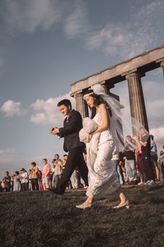 Newlyweds celebrate at a wedding ceremony near iconic Edinburgh columns, Scotland.