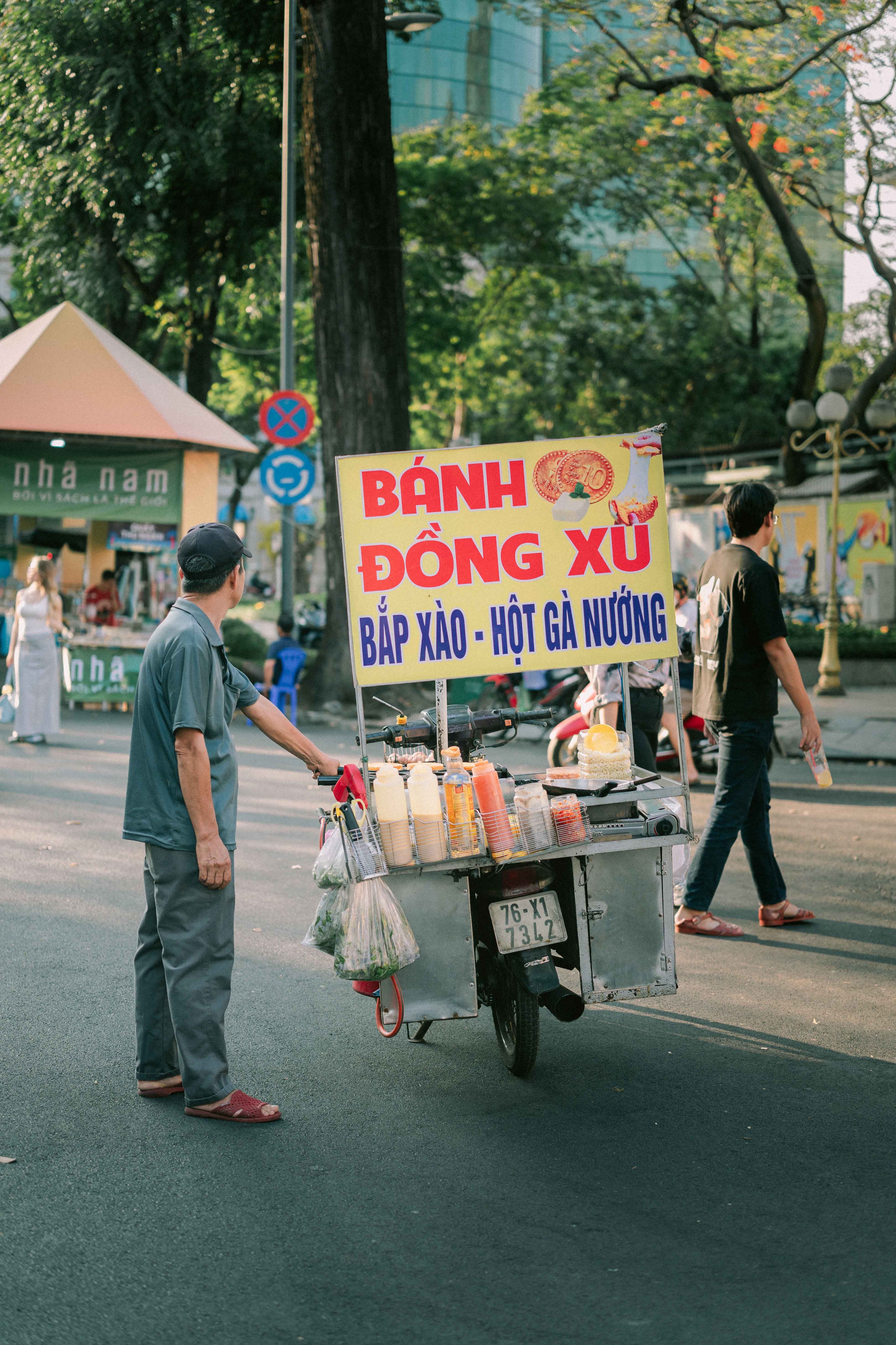A street food vendor with a portable stall in bustling Ho Chi Minh City, Vietnam street.