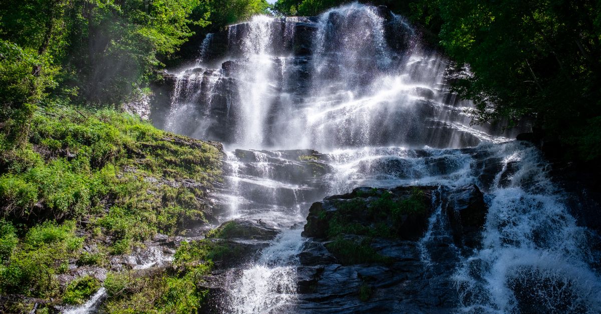 Stunning waterfall cascading in a vibrant forest landscape during the day.