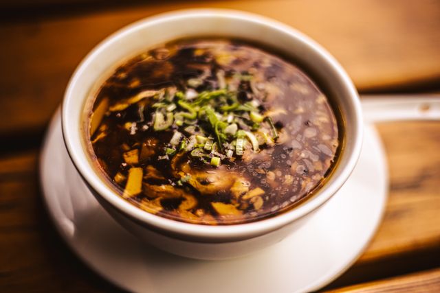 Appetizing hot and sour soup in a bowl garnished with fresh herbs.