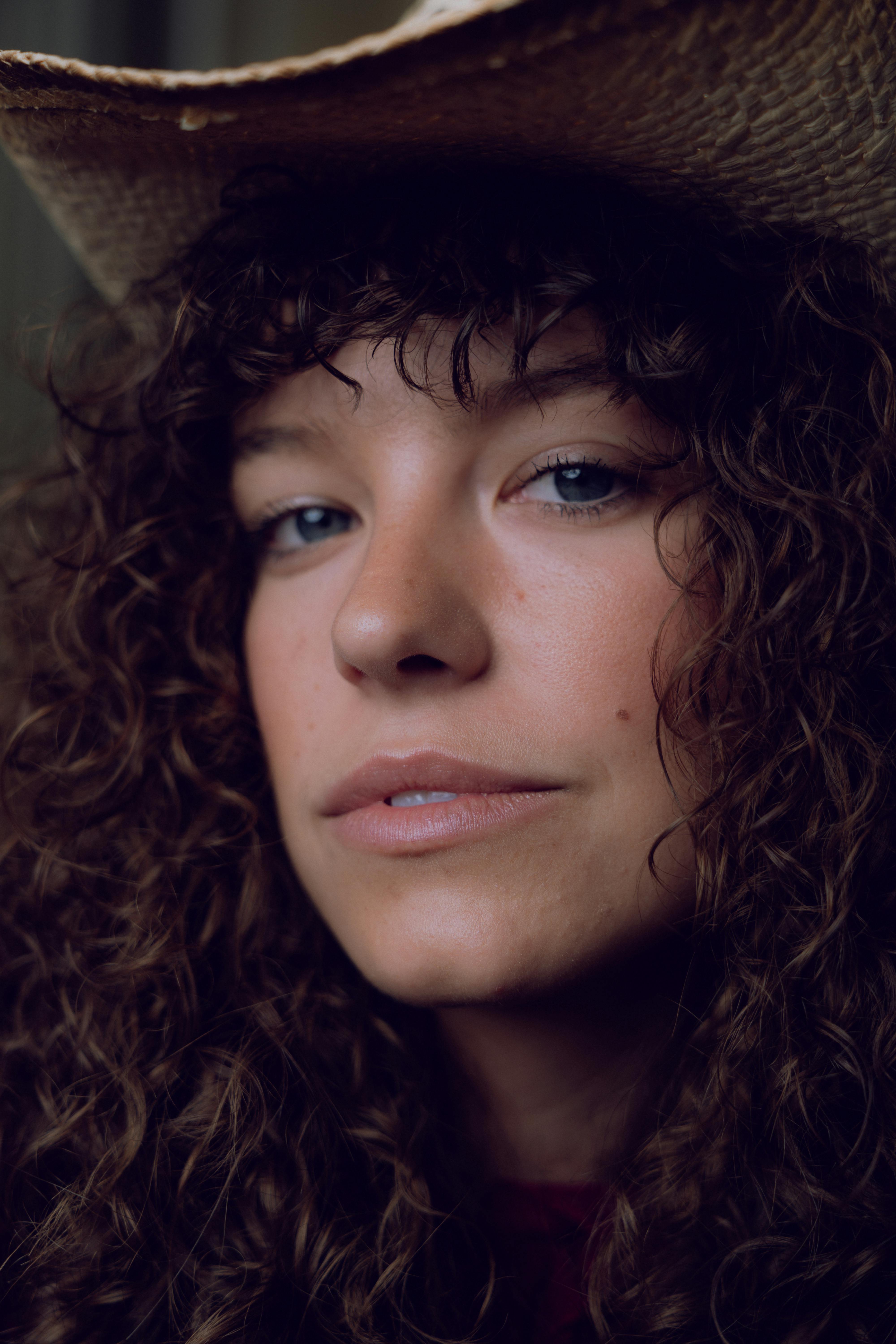 a woman with curly hair wearing a cowboy hat