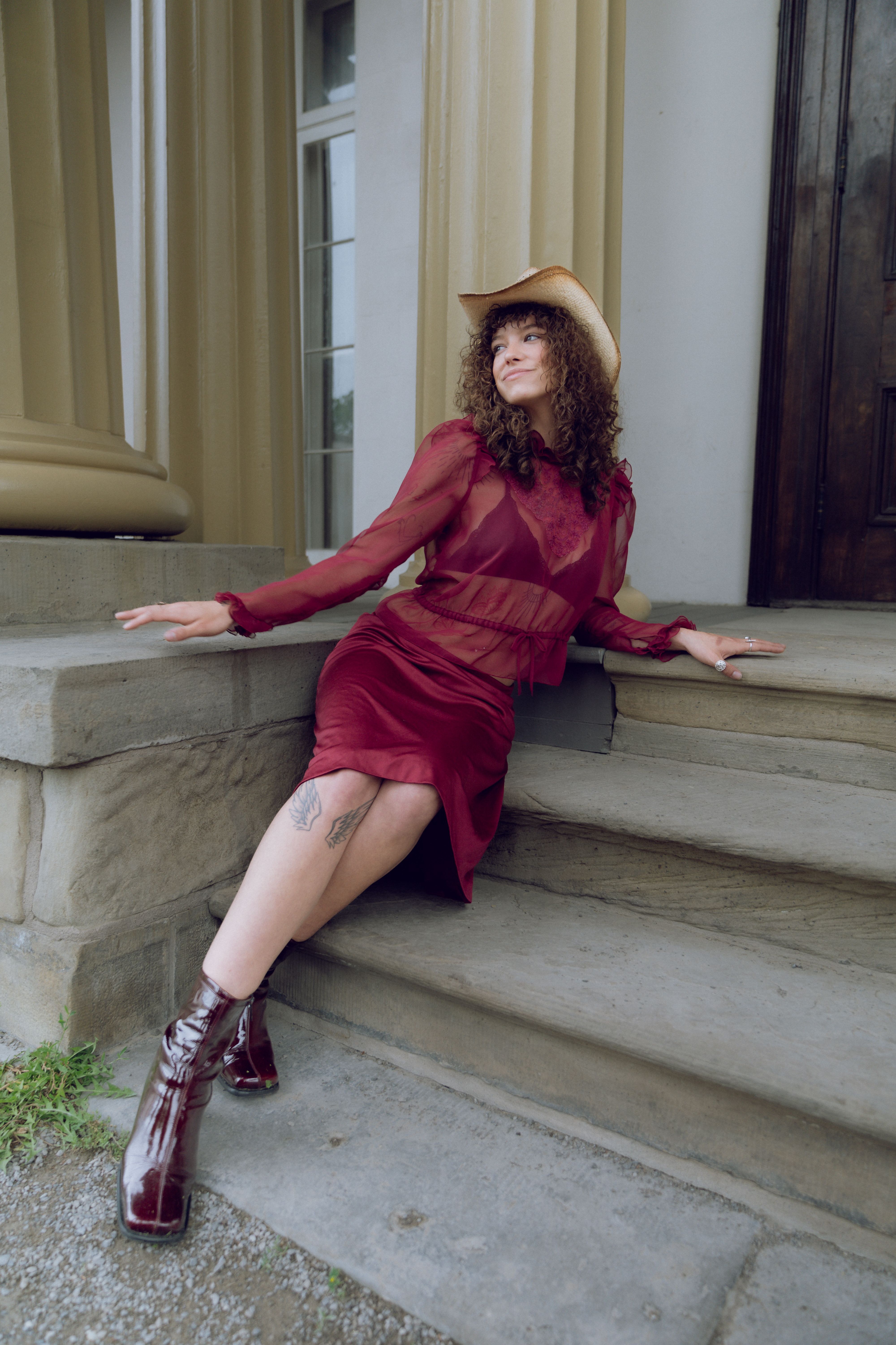 A woman in a red dress and hat sitting on steps · Free Stock Photo