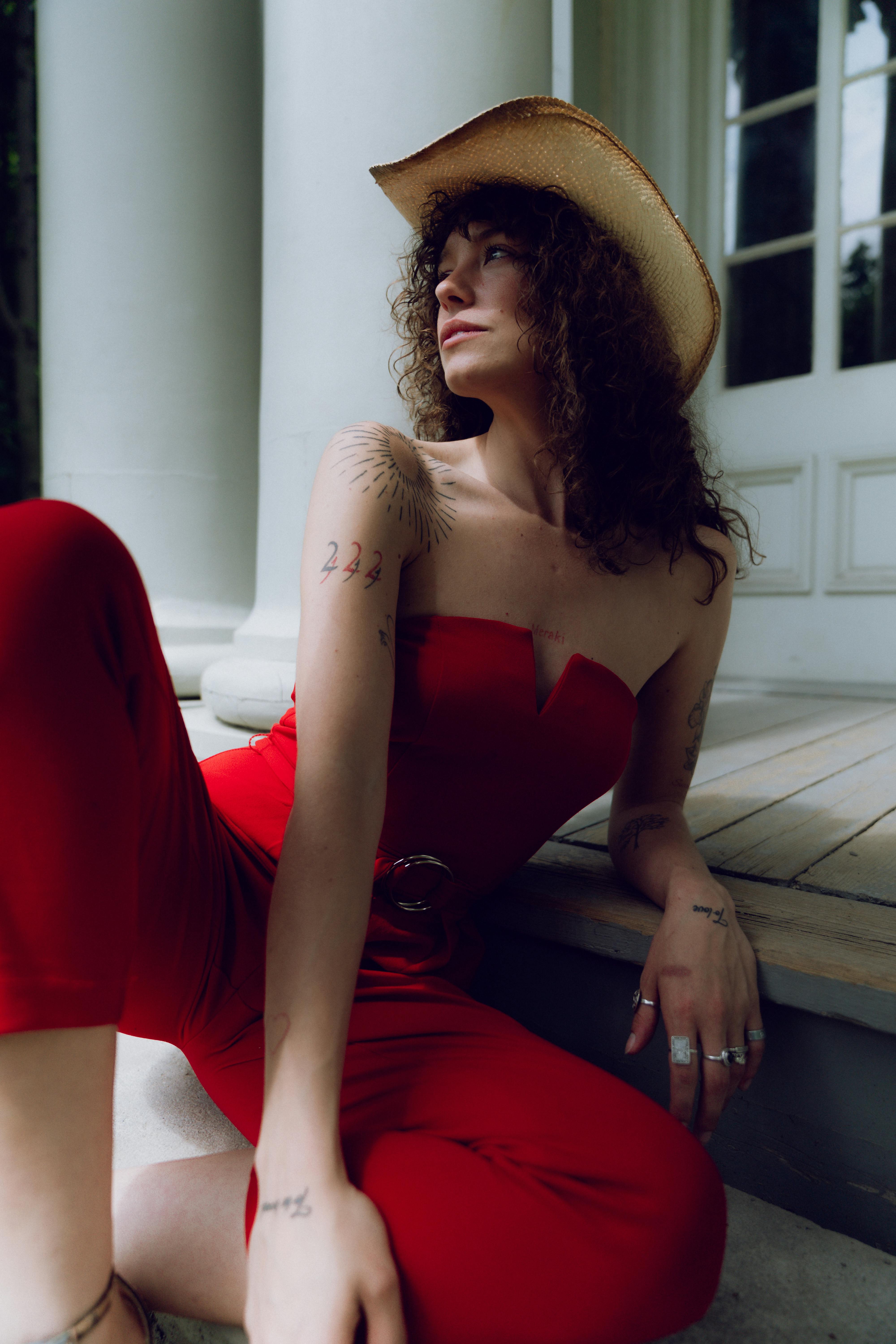 a woman in a red jumpsuit and cowboy hat