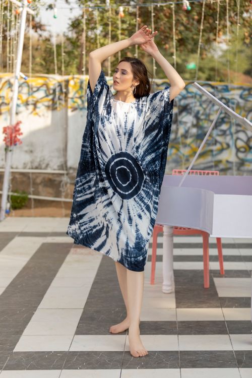 Free Fashionable young woman poses confidently outdoors in a blue and white tie-dye kaftan, exuding elegance. Stock Photo